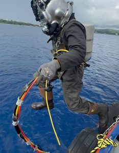 diver jumping into water holding fiber optic cables to be installed