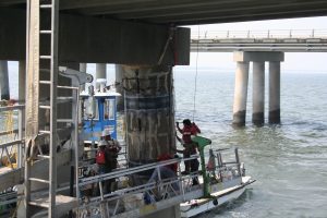4 precon marine construction workers inspecting a bridge pile and marking it for construction