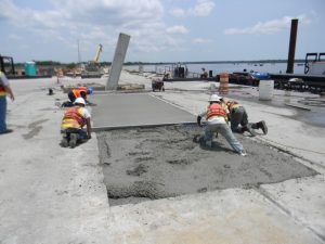 Precon Marine construction workers smoothing concrete for dock repairs