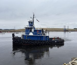 transportation (2) (1) tugboat name Ida M floating in a river with crew members checking on it's railing