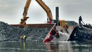 crane lifting stone and rock to install riprap shoreline