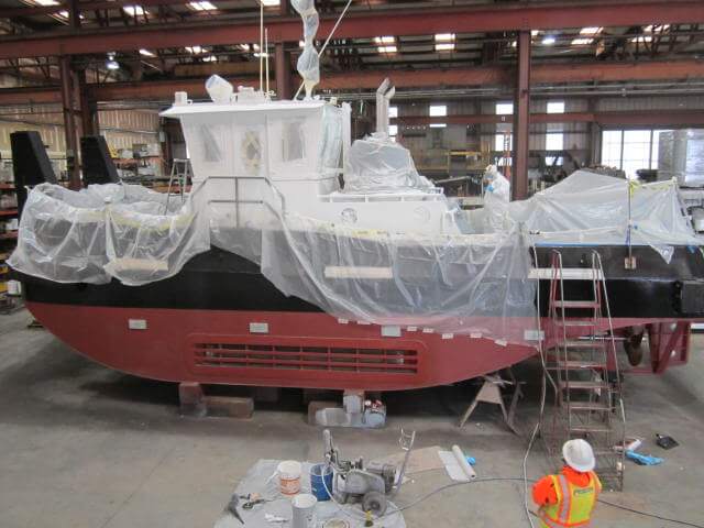 fabricated tugboat being coated with protected paint