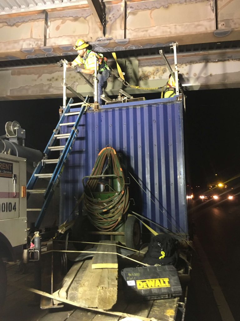 IMG_0320 precon marine worker, on top of scaffolding, describing the size of a repair to another workers offscreen