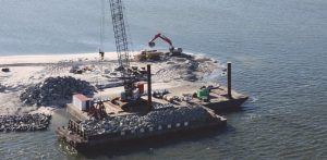 precon marine crane on barge being used to install riprap on shoreline