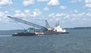 tugboat transporting crane on barge to be used for rental services