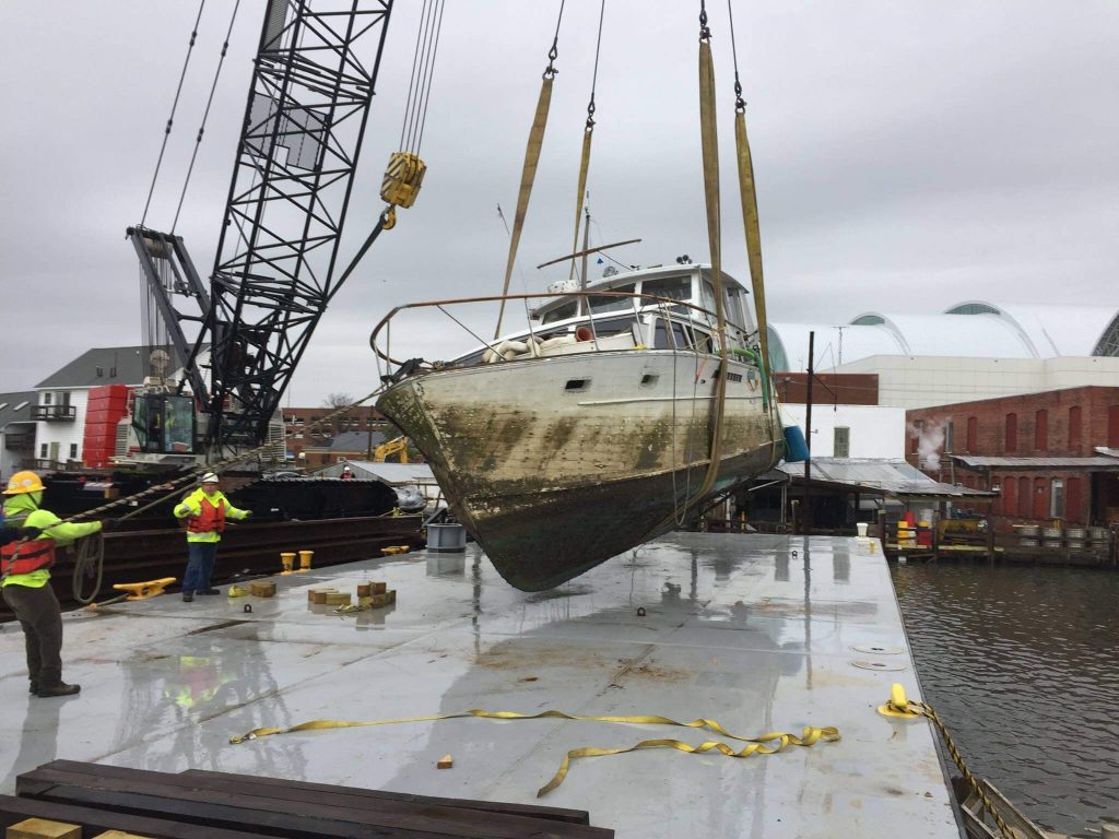 Crane collecting stuck vessel and placing on barge for repairs